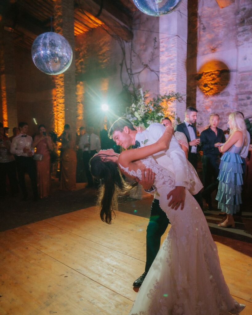 Couple dancing among guests under mirror balls